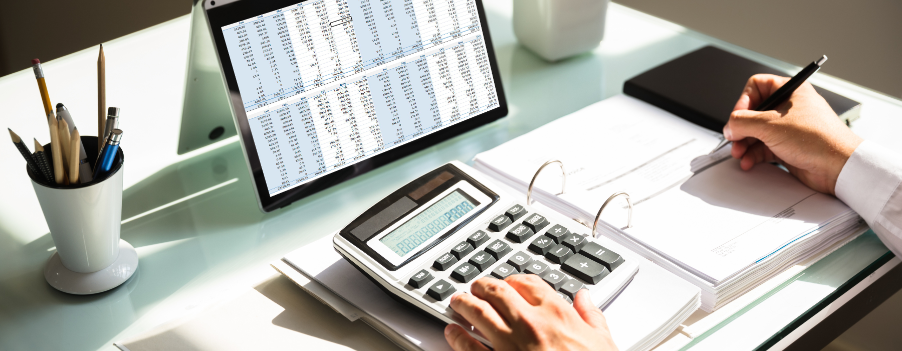 A close-up of a professional’s hands using a tablet or computer with visible invoice or payment data on the screen